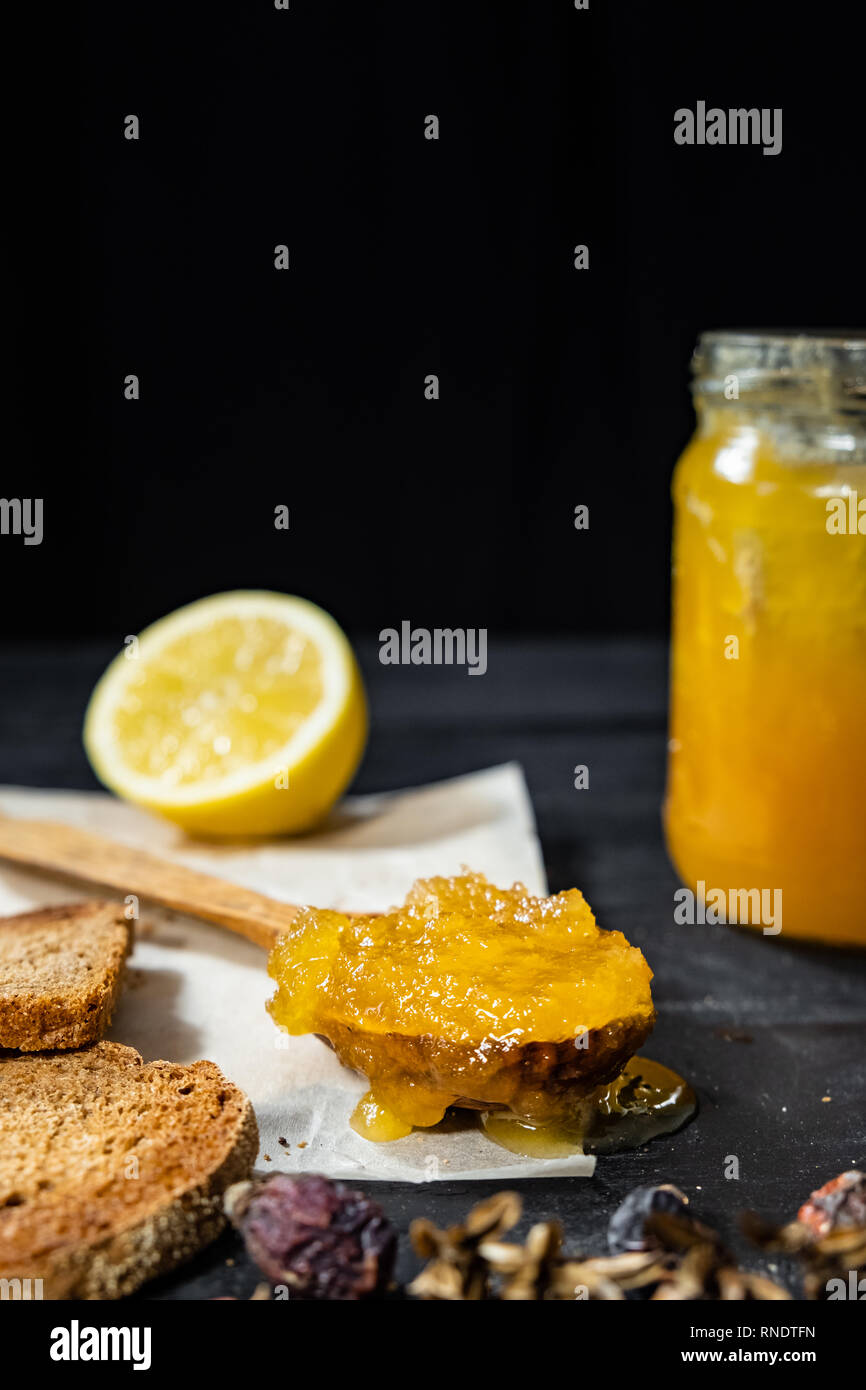 Spoonful of honey on dark rustic background. Crystallized home-made honey in jar, low-key shot with copy space Stock Photo