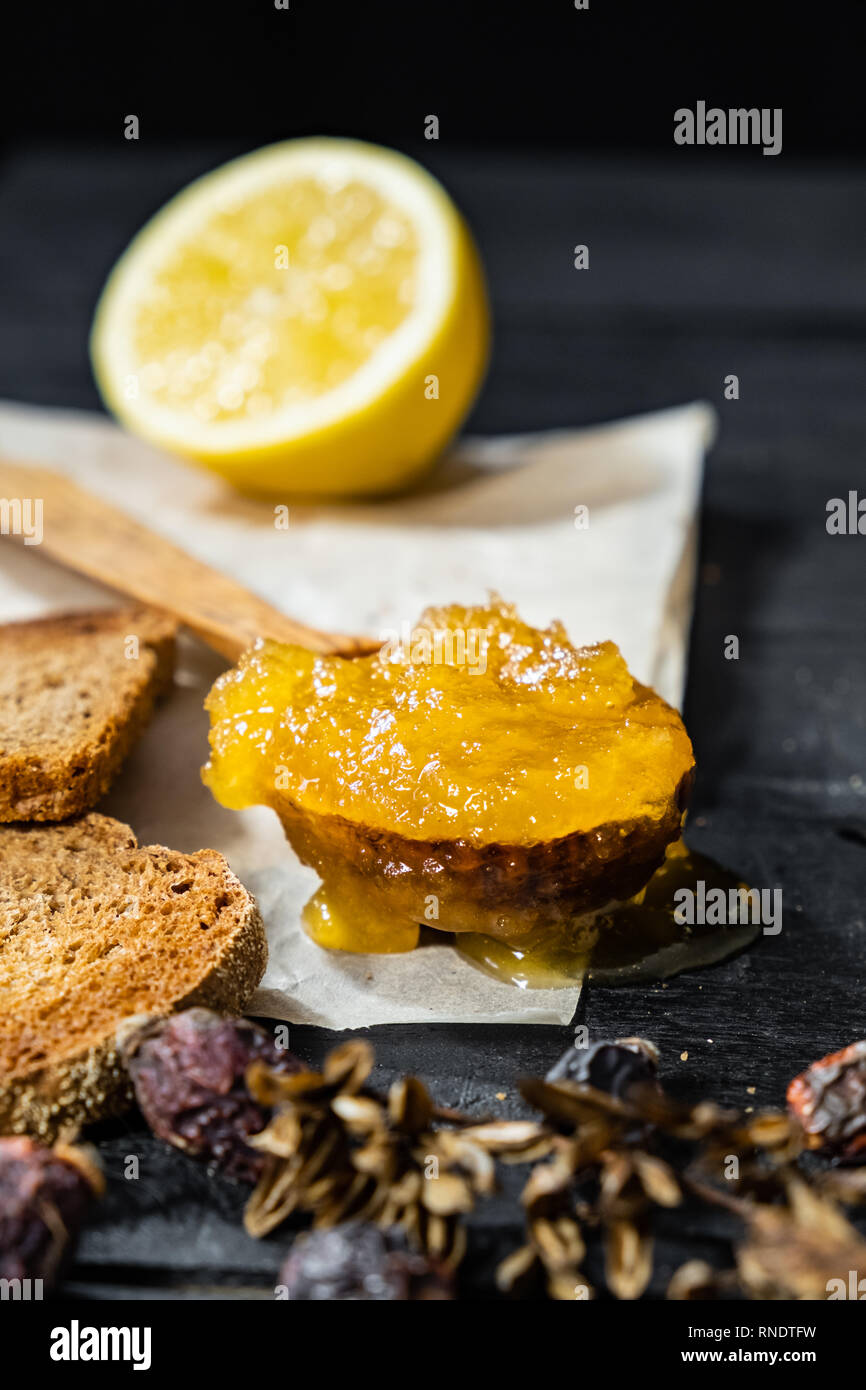 Spoonful of honey on dark rustic background. Crystallized home-made honey in wooden spoon, low-key shot Stock Photo