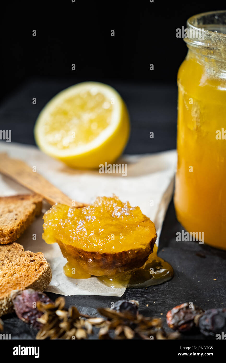 Spoonful of honey on dark rustic background. Crystallized home-made honey in jar, low-key shot Stock Photo