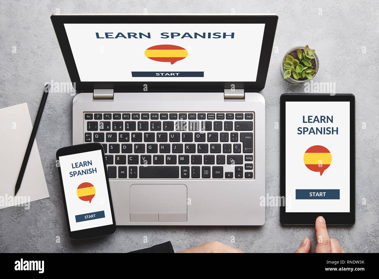 Learn Spanish concept on laptop, tablet and smartphone screen over gray table. All screen content is designed by me. Flat lay Stock Photo