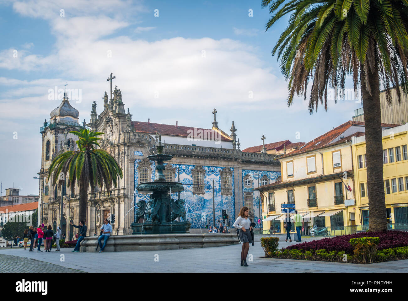 Old town center view of tourists palm trees and Carmelitas church with iconic Portuguese tile work in Porto north Portugal. Stock Photo