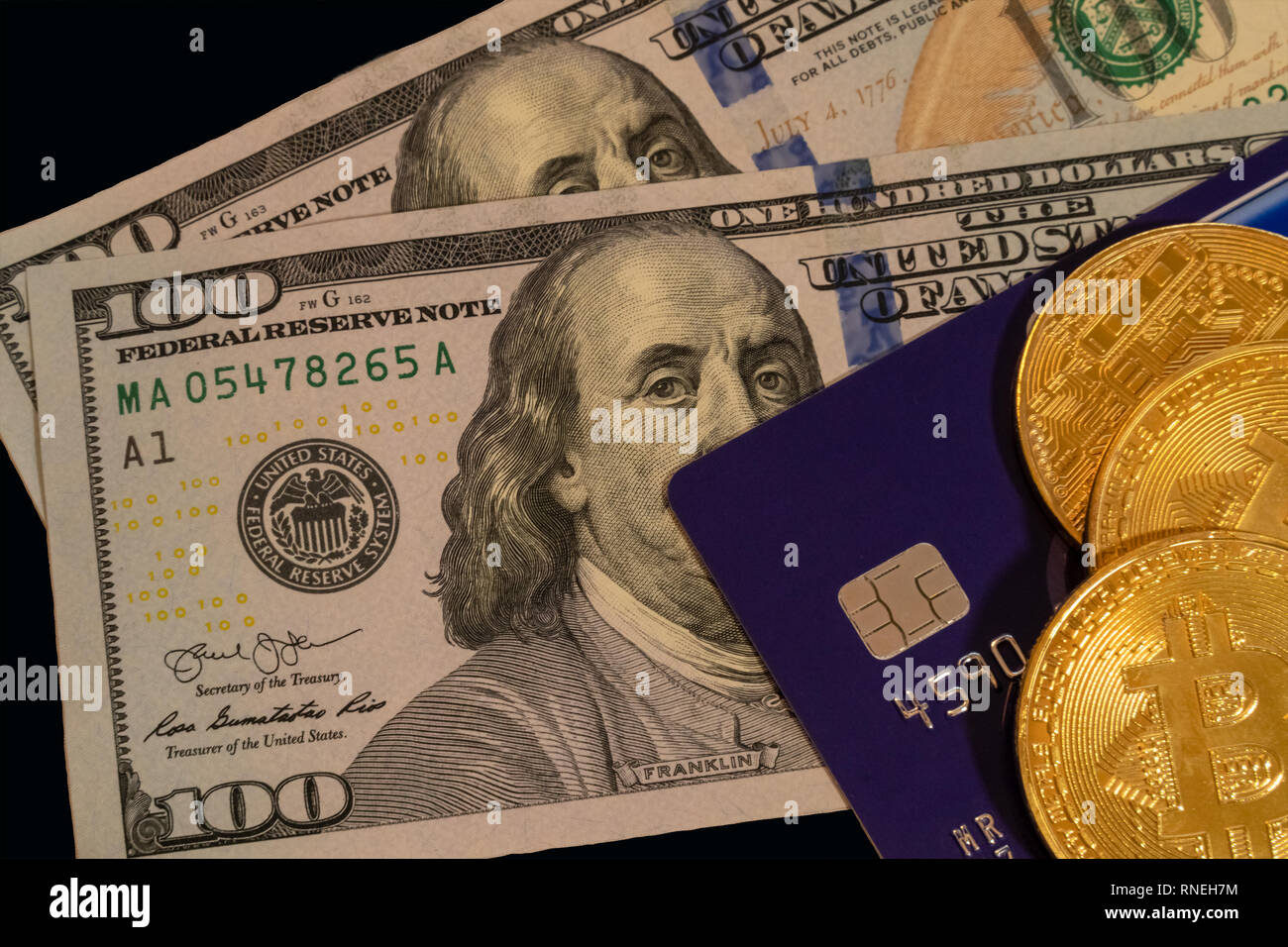 Golden bitcoin with blue credit card on top of hundred dollars banknote background, cryptocurrency accepting for payment and finance concept Stock Photo