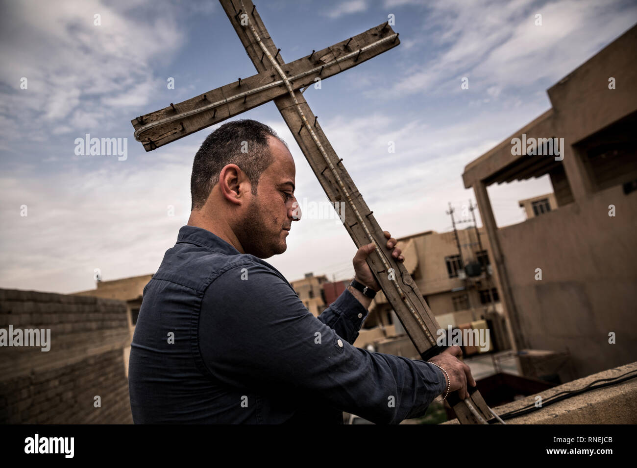 The former Christian war hero Husam S Tosh erects a wooden cross on the roof of a house in Karakosch near Mossul, which was used by the IS as a base camp and is used today as Christian party headquarters. The Christian population was expelled by the IS, but many return to their homes in the surrounding Christian villages. Some churches could be rebuilt, so that church services can take place there again. Nevertheless, the Christians are now threatened by the Shiite conquerors of the province Ninawa and the capital Mossul and more and more repressed, so that the Christians do not have good pers Stock Photo
