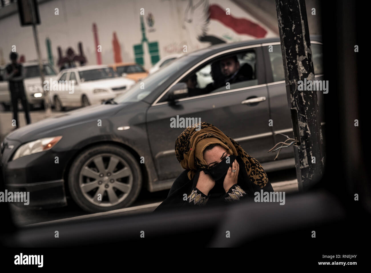 Veiled beggar on a street in the center of Mossul. After the liberation from the IS, normality slowly returns to the maltreated city, but there is a lot of poverty. Stock Photo