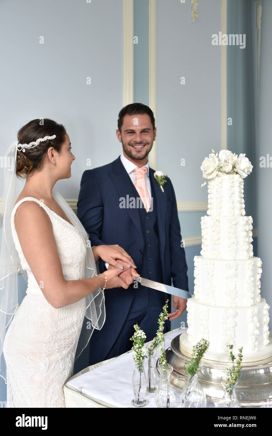 Beautiful white couple get married by the sea on a glorious Summer day in a traditonal white wedding Stock Photo