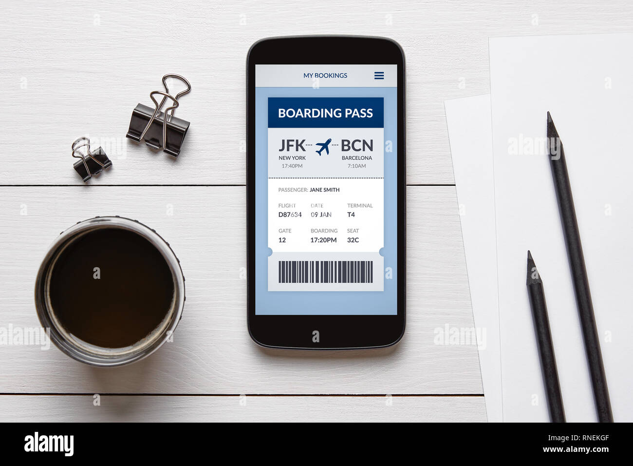 Boarding pass concept on smart phone screen with office objects on white wooden table. All screen content is designed by me. Flat lay Stock Photo