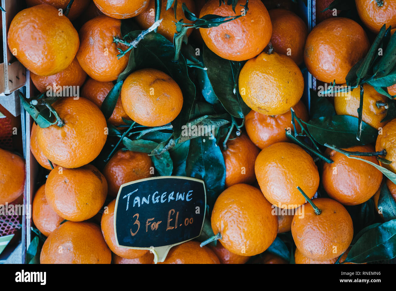 Pile of fresh satsumas with stems and leaves on sale at a street market