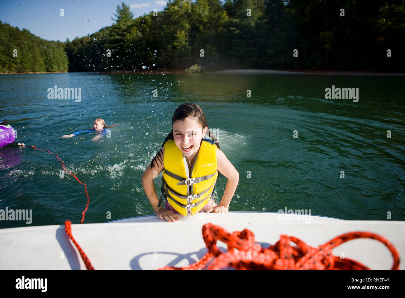 Girl climbing out of water to get on a boat Stock Photo Alamy