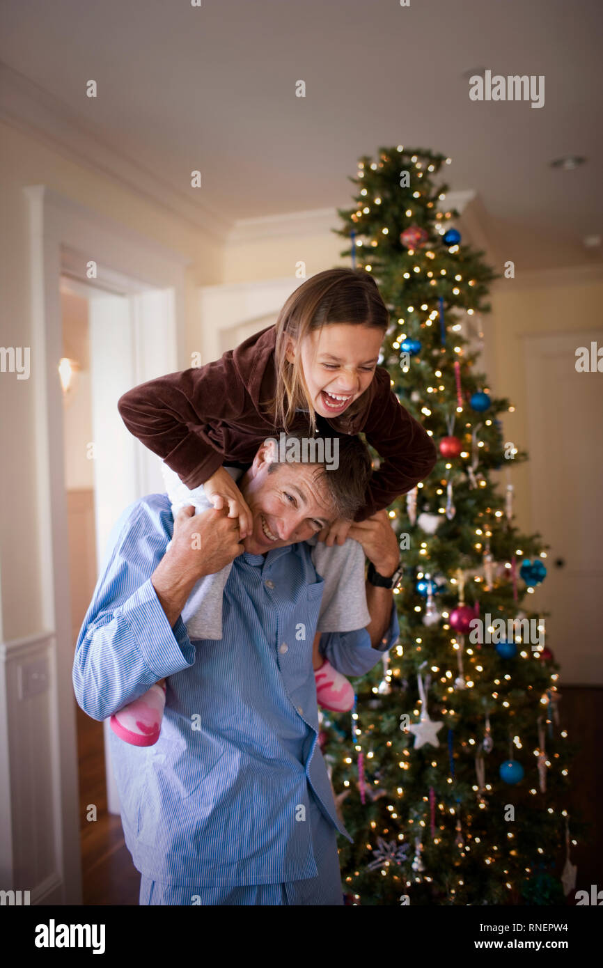 laughing-young-girl-sitting-on-her-father-s-shoulders-on-christmas-day