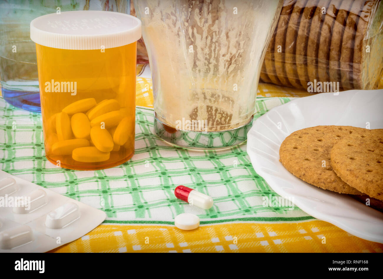 Medication during breakfast, capsules next to a glass of water, conceptual image, horizontal composition Stock Photo