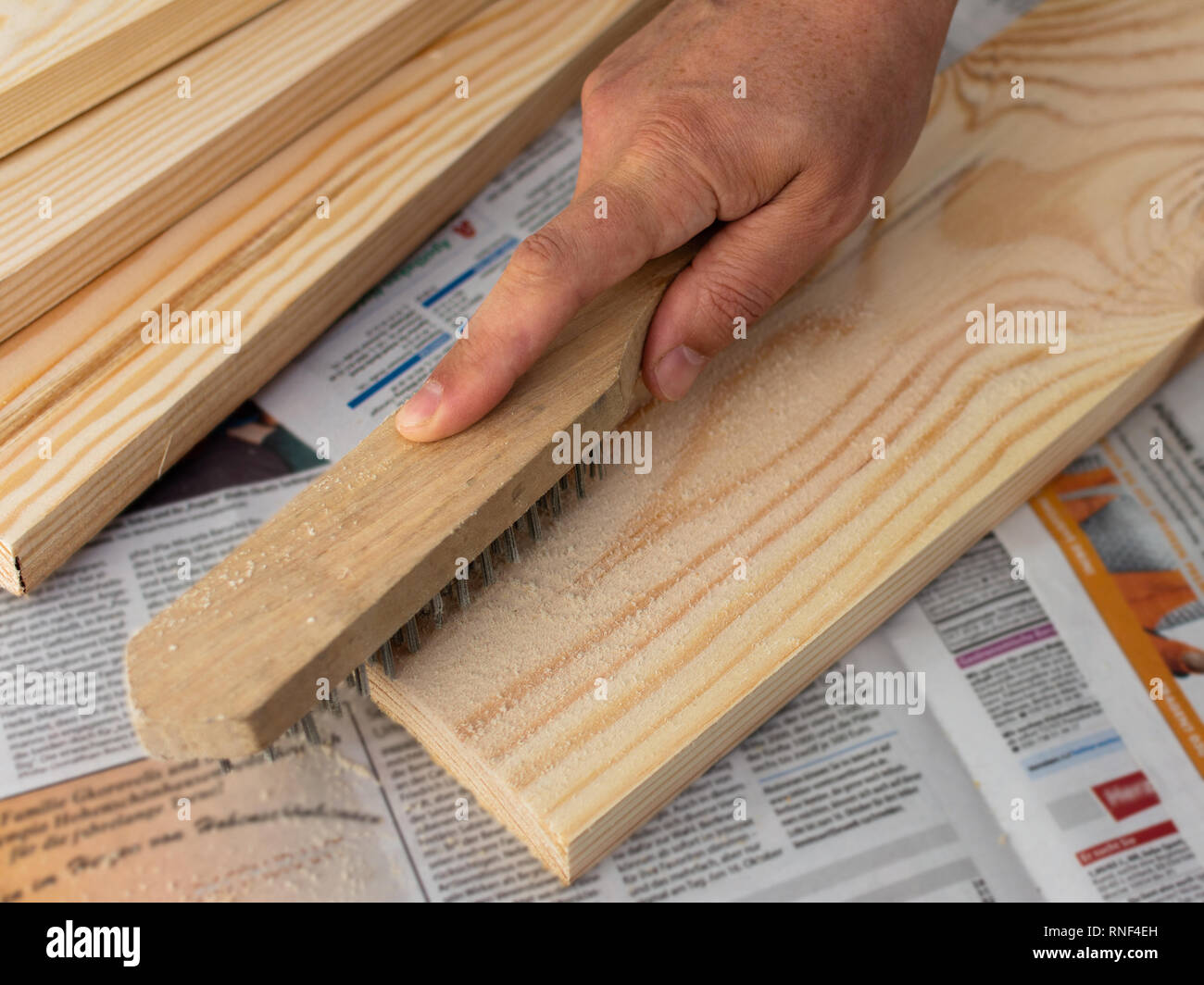 Man's hand with steel abrasive brush revealing the structure of the