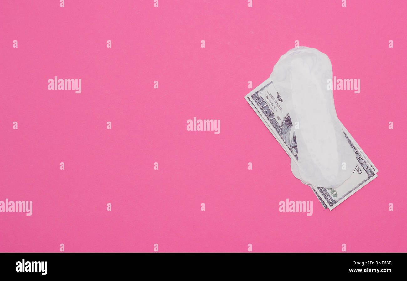 Women's pads and money dollars on a pink background, the cost of hygiene products, copy space, periodicity, intimate Stock Photo