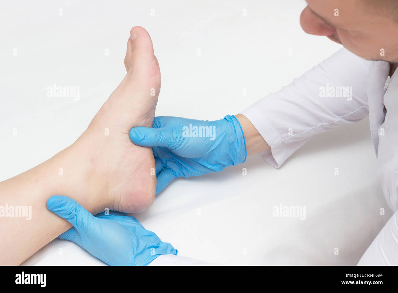 Doctor examines the patient's leg with heel spurs, pain in the foot, white background, close-up, plantar fasciitis, inspection Stock Photo