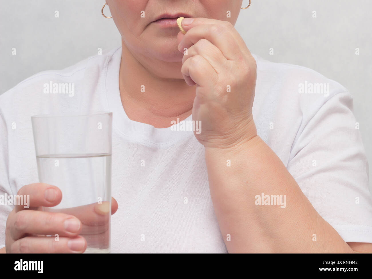 A woman drinks a hormonal pill for treating the thyroid gland, eliminating nodules and normalizing hormones. treatment, close-up, Hypothyroidism, Thyr Stock Photo