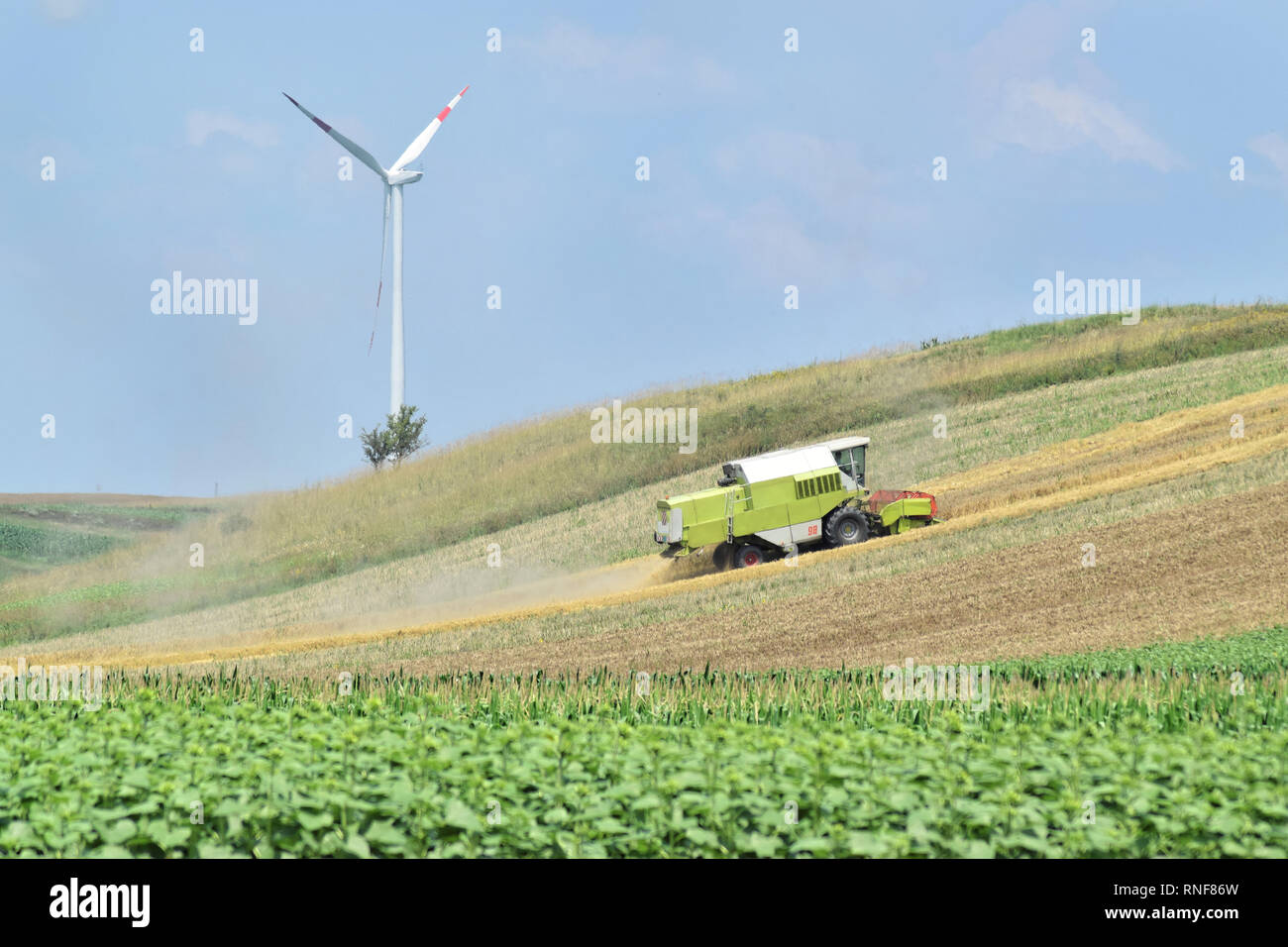Combine harvester working in the farmland during spring and wind farm ...