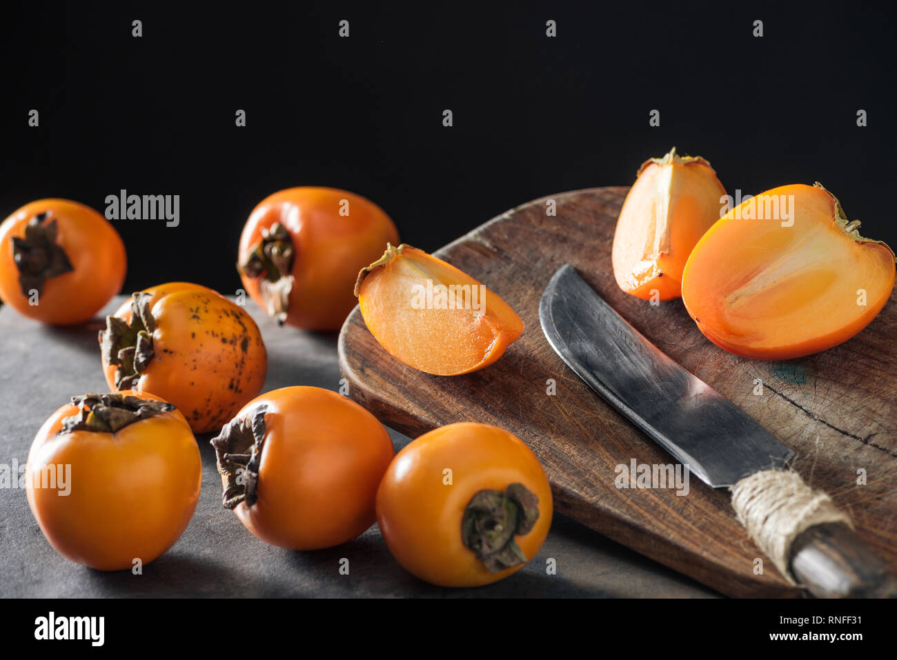 ripe and orange persimmons on cutting board with knife Stock Photo