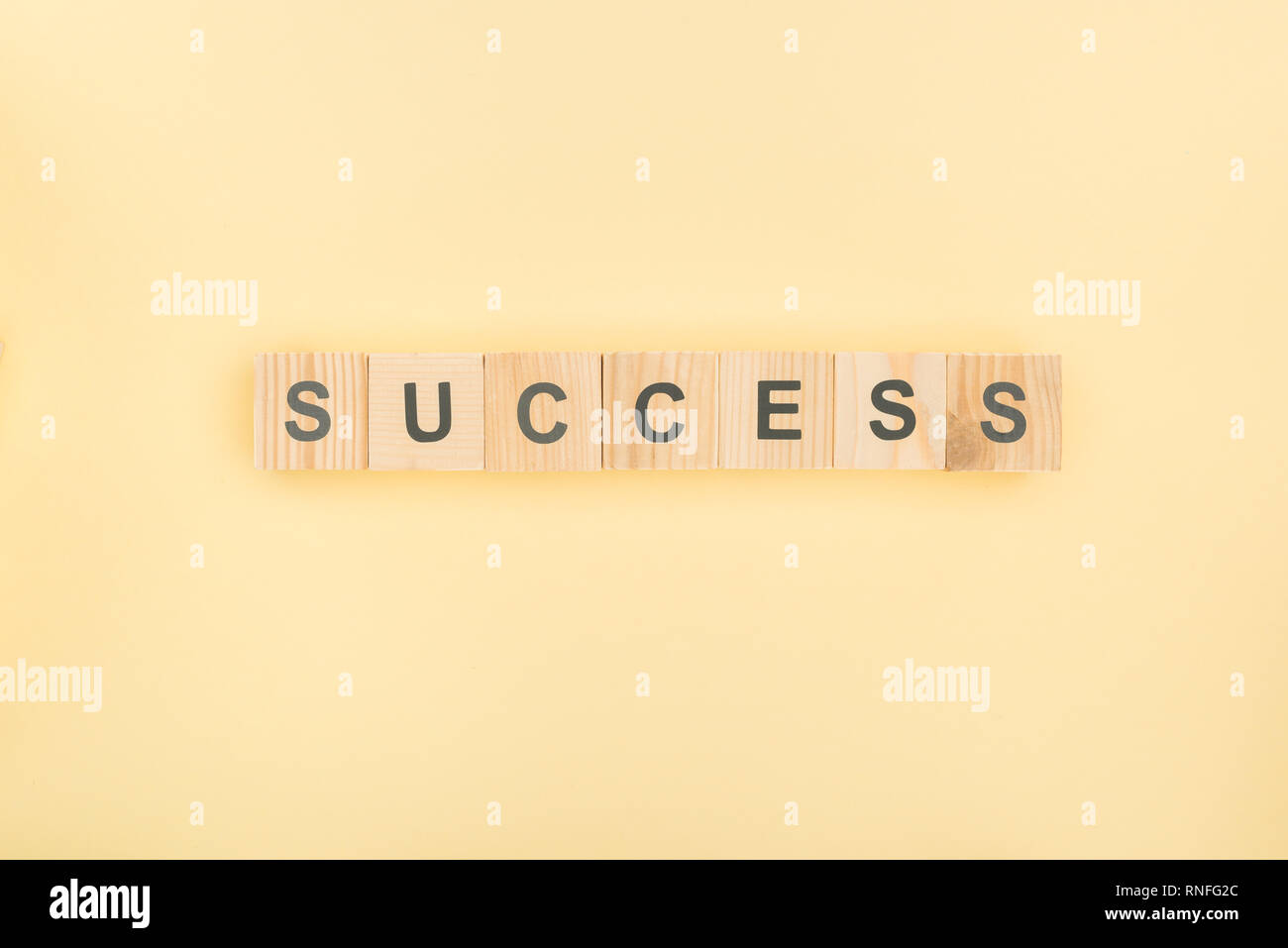 top view of success lettering made of wooden cubes on yellow background Stock Photo