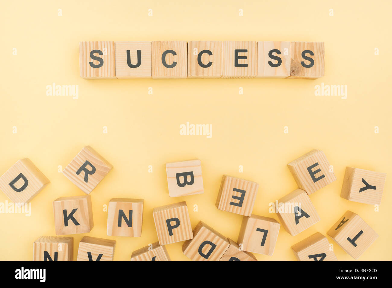 top view of success lettering with wooden cubes on yellow background Stock Photo