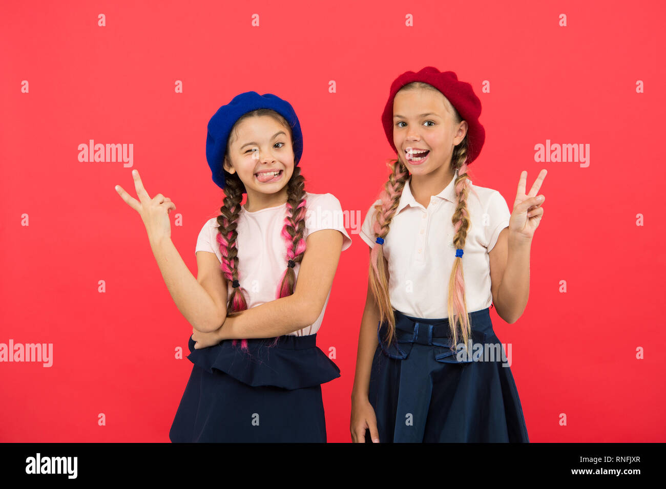 Making peace signs. French style girls. Little kids wearing stylish french  berets. Cute girls having the same hairstyle. Small children with long hair  plaits. Fashion girls with tied hair into braids Stock