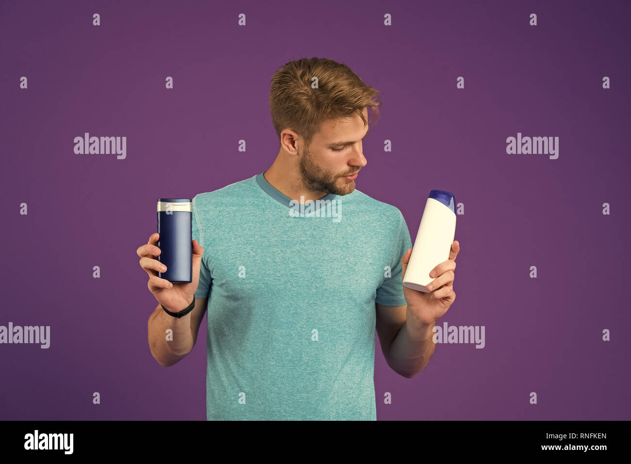 Man on thoughtful face chooses shampoo, violet background. Guy with