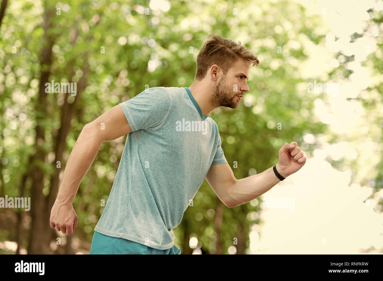 Moving to his goal. Man confident young running in park, side view. Sportsman ambitiously moves to achieve sport goal. Masculinity and sport achievements concept. Guy concentrated runs for his goal. Stock Photo