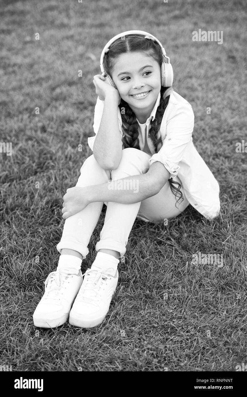 Positive influence of music. Child girl enjoying music modern earphones. Childhood and teenage music taste. Little girl listening music enjoy favorite song. Girl with headphones nature background. Stock Photo
