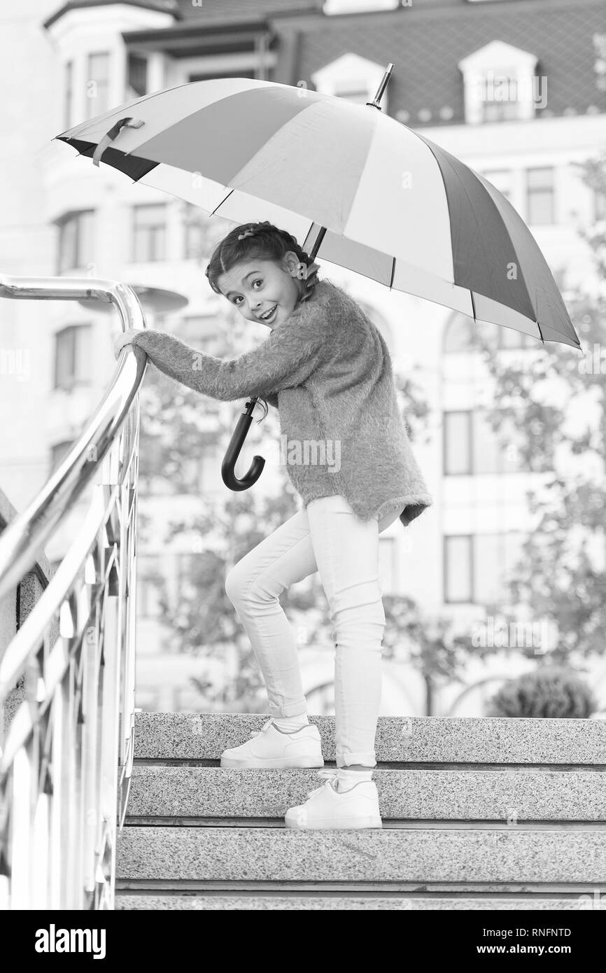 Girl standing on stairs and holding umbrella. Autumn rain. Waiting for bad weather under umbrella. Stylish girl in downtown. Positivity as resistance to cold. Beautiful lady going for a walk. Stock Photo