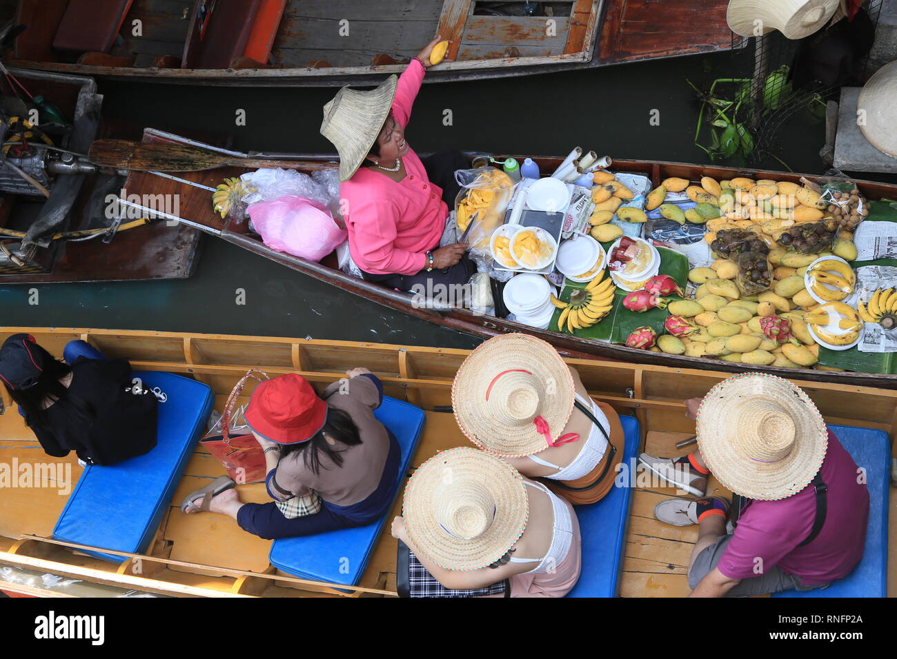 Bangkok Thailand - December 2016: Boats on canal selling fruits, foods, hats for tourists in Damnoen Saduak floating market. Stock Photo