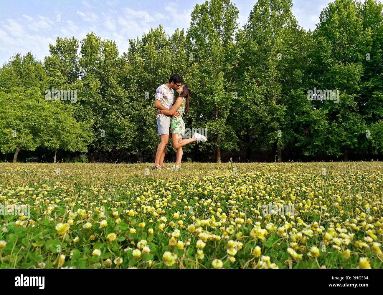 Happy loving couple kissing each other in a field full of yellow flowers. Stock Photo
