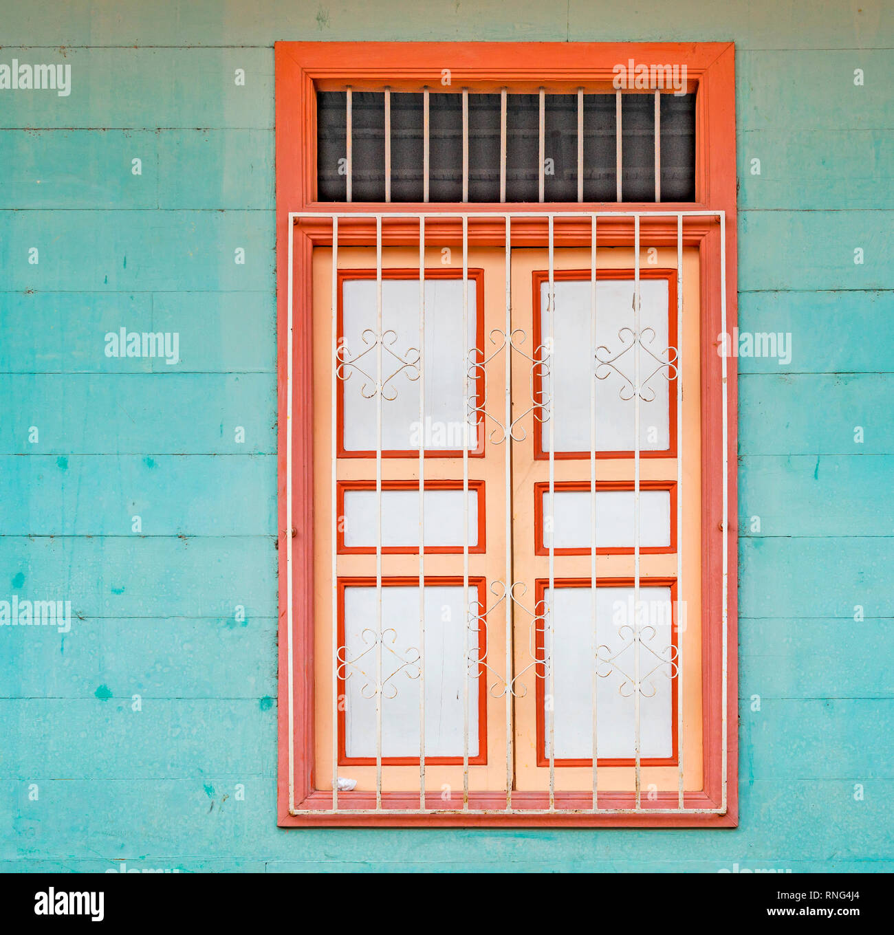Square photograph of a turquoise wooden wall with orange and white window in the city center of Guayaquil, Ecuador. Stock Photo