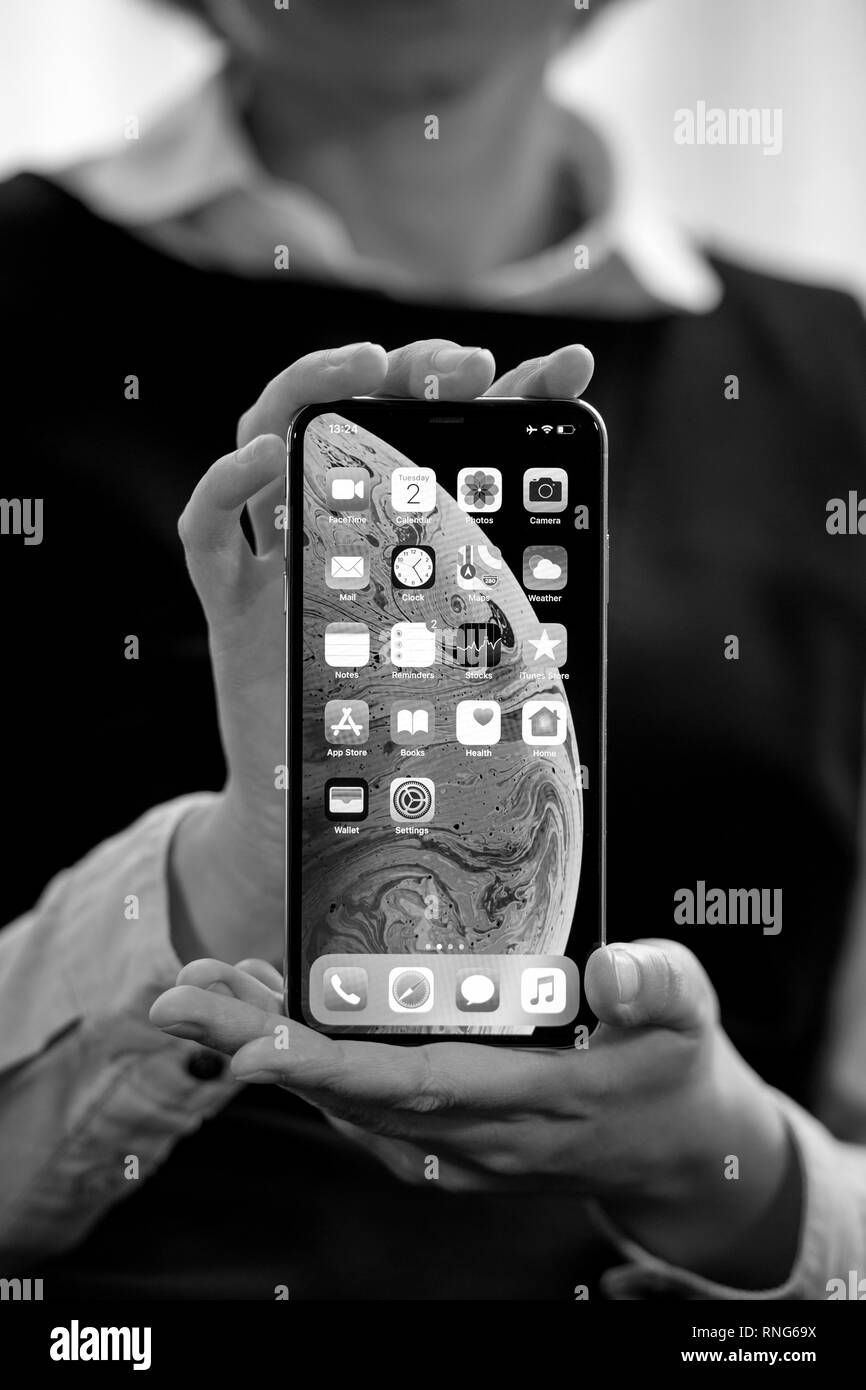 PARIS, FRANCE - OCT 2, 2018: business woman demonstration of the new Apple iPhone Xs Max smartphone telephone from Apple Computers with all home apps on OLED display - black and white Stock Photo