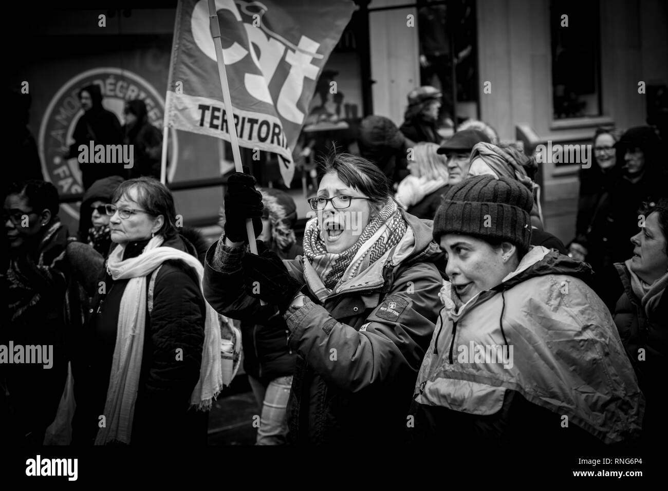 STRASBOURG, FRANCE - MAR 22, 2018: Young woman proteting holding CGT General Confederation of Labour flag with other  workers holding placards at demonstration protest against Macron French government string of reforms - black na dwhite Stock Photo