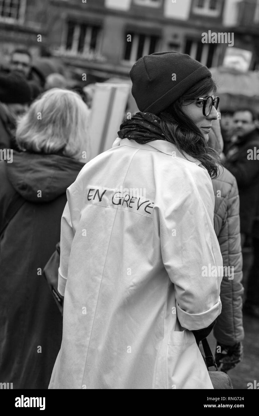 STRASBOURG, FRANCE - MAR 22, 2018: People gathering in Place Kleber square during CGT General Confederation of Labour demonstration protest against Macron French government string of reforms - rear view of young nurse in white coat Stock Photo