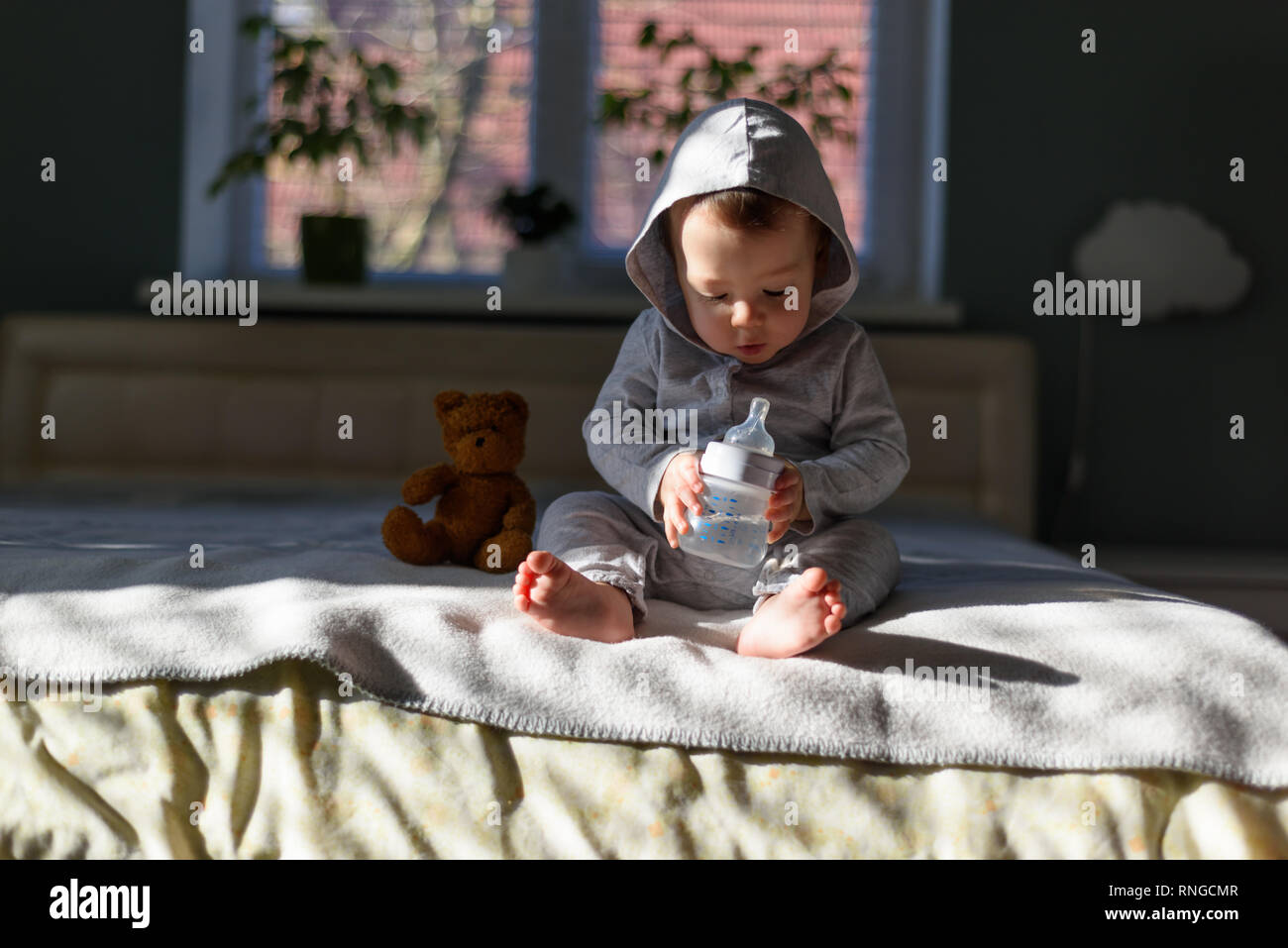Baby boy with coloured pyramid toy on bed in his room Stock Photo