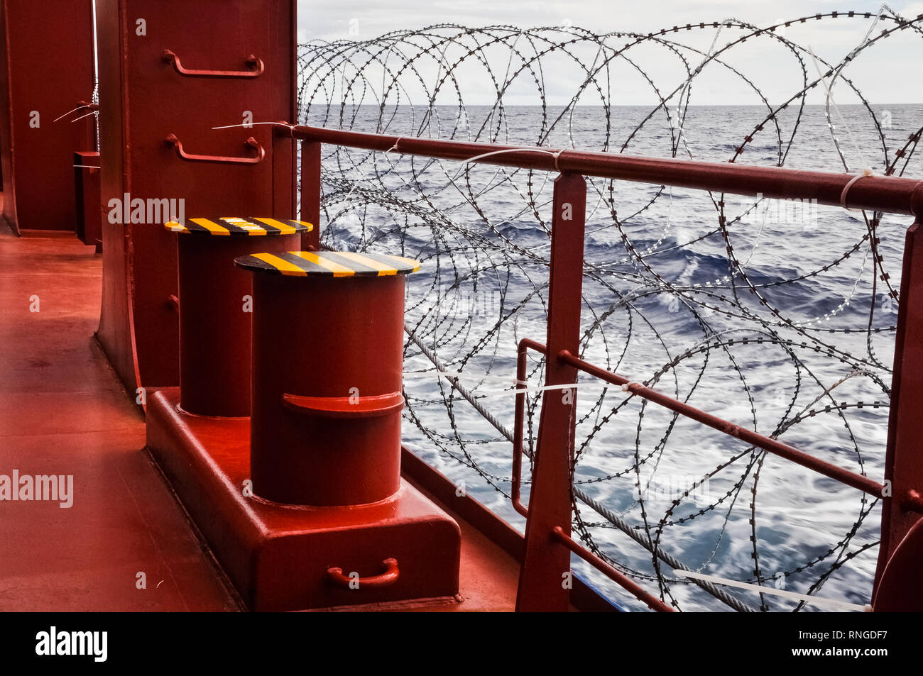 Pirate protection measures onboard of a merchant ship passing pirate high risk area, Babed wire on a ship railing. Pirate protection concept. Backgrou Stock Photo