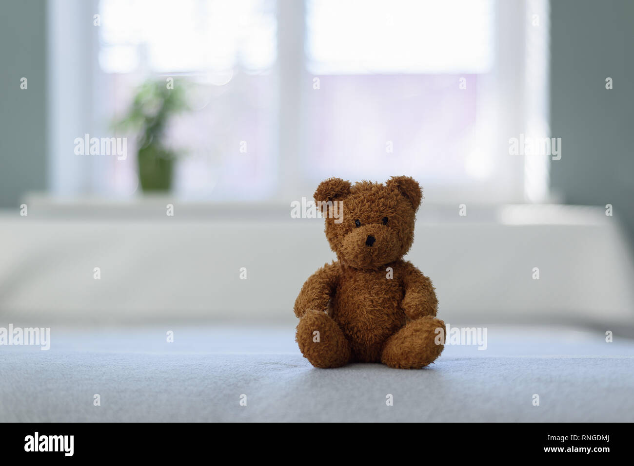 Plush teddy bear toy on white bed. Childhood concept Stock Photo