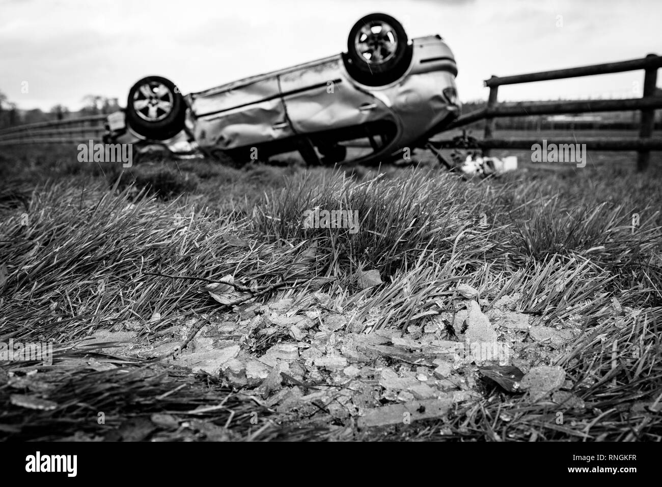 Car Crash and Car Damage. Vehicle upside down in a field surrounded by broken glass and debris after a high speed crash. Stock Photo