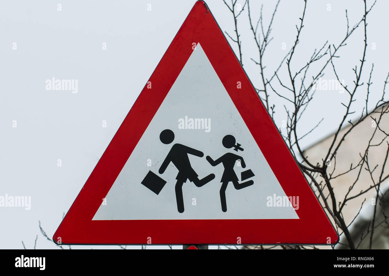 Warning street sign close to the pedestrian crossing near a school Stock Photo