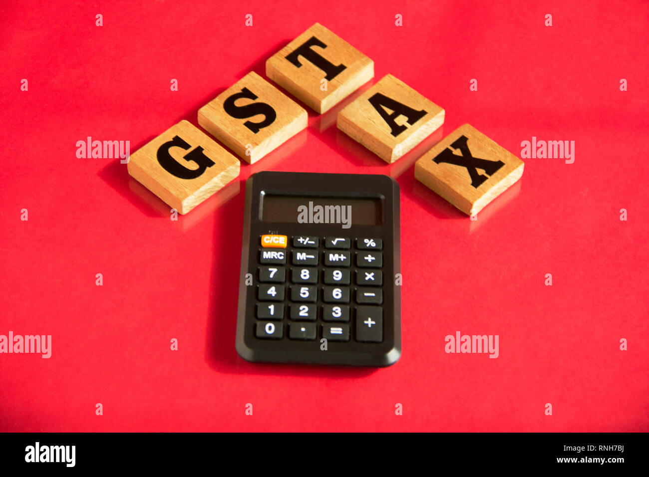 GST and TAX wooden letters words with calculator on a red background, financial concept Stock Photo
