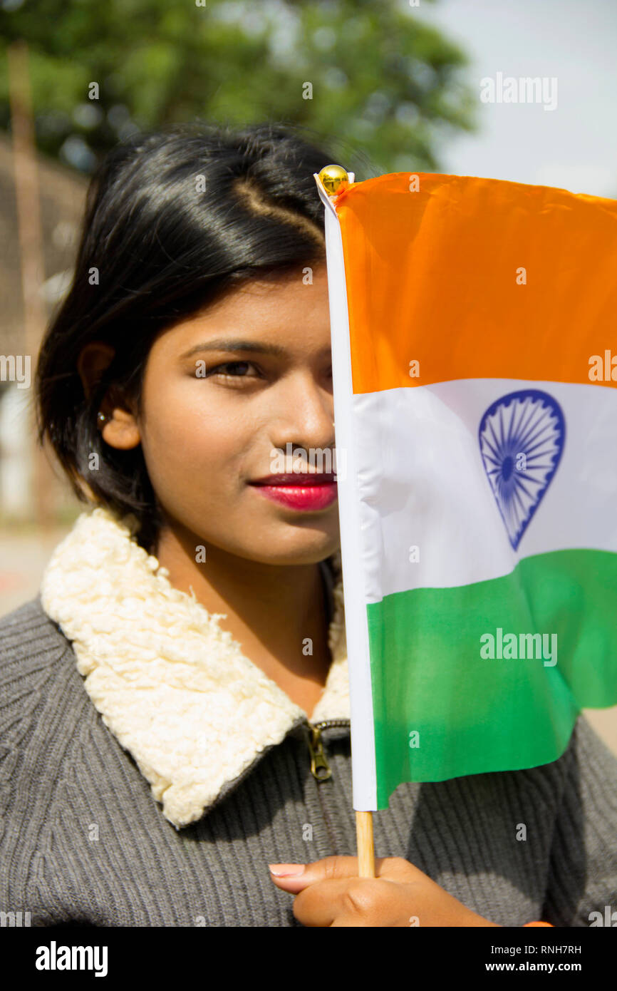 Close-up of young Indian girl holding Indian National flag covering half her face, Pune Stock Photo