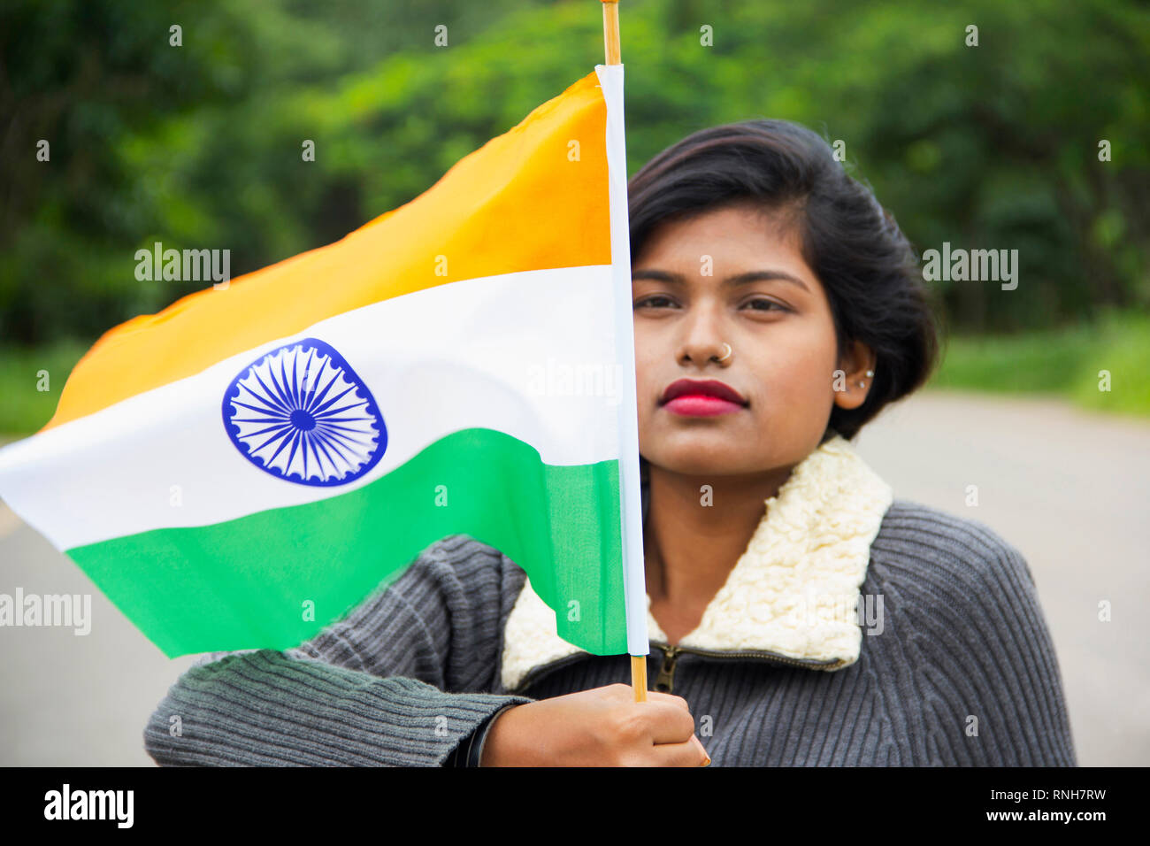 Close-up of young Indian girl holding Indian National flag and looking at it with pride, Pune Stock Photo