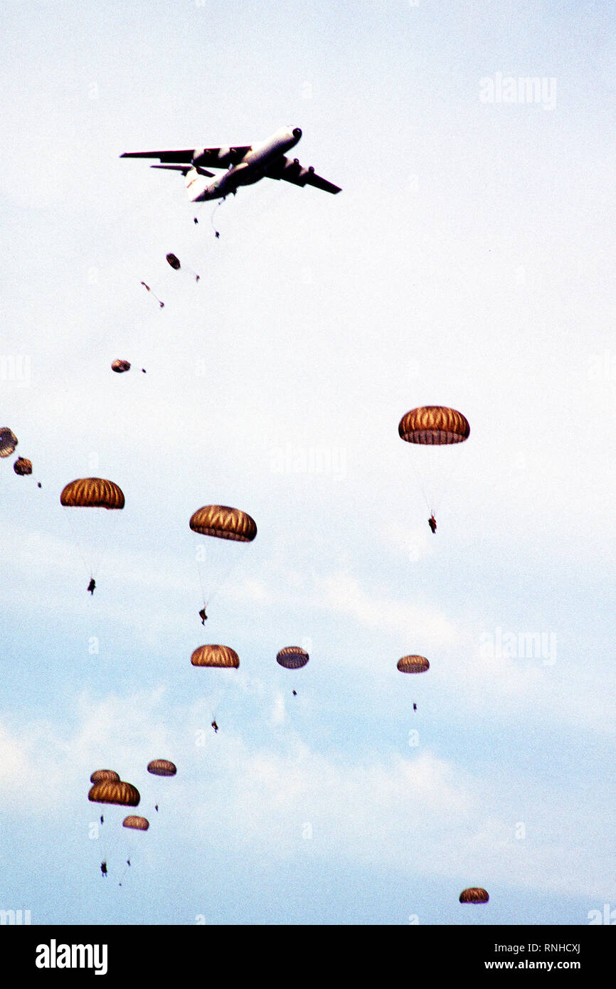 Paratroopers descend from C-141B Starlifter aircraft over Drop Zone B-70 during Dragon Team, the largest non-Joint Chiefs of Staff airdrop training exercise in history. Stock Photo