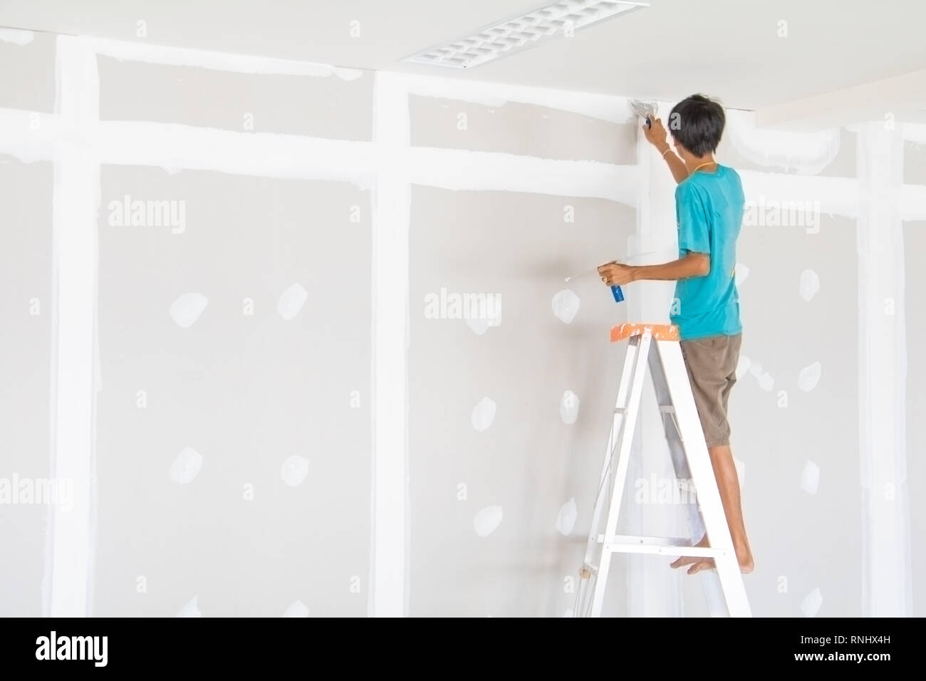 worker male on stair is putting  gypsum plaster interior decoration of home wall Stock Photo