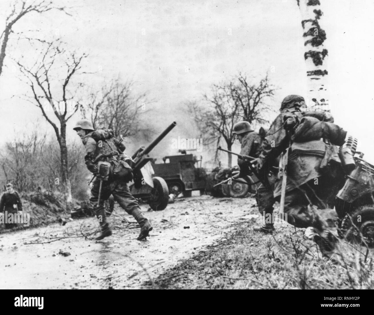 German troops advancing past abandoned American Equipment - Panzergrenadier-SS Kampfgruppe Hansen in action during clashes in Poteau against Task Force Myers, 18 December 1944. Stock Photo