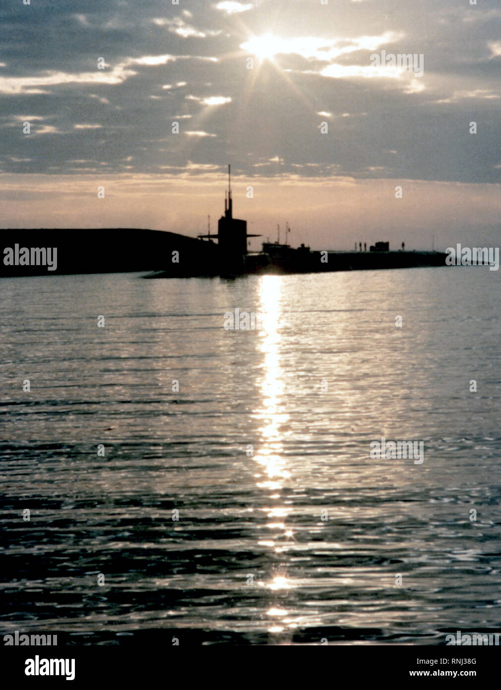 1982 - A port bow view of the nuclear-powered strategic missile submarine USS OHIO (SSBN-726) silhouetted against the setting sun. Stock Photo