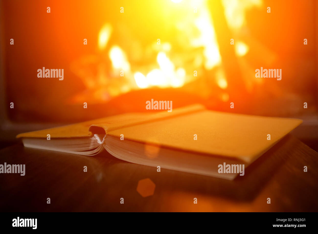 open book on the background of a burning fireplace Stock Photo