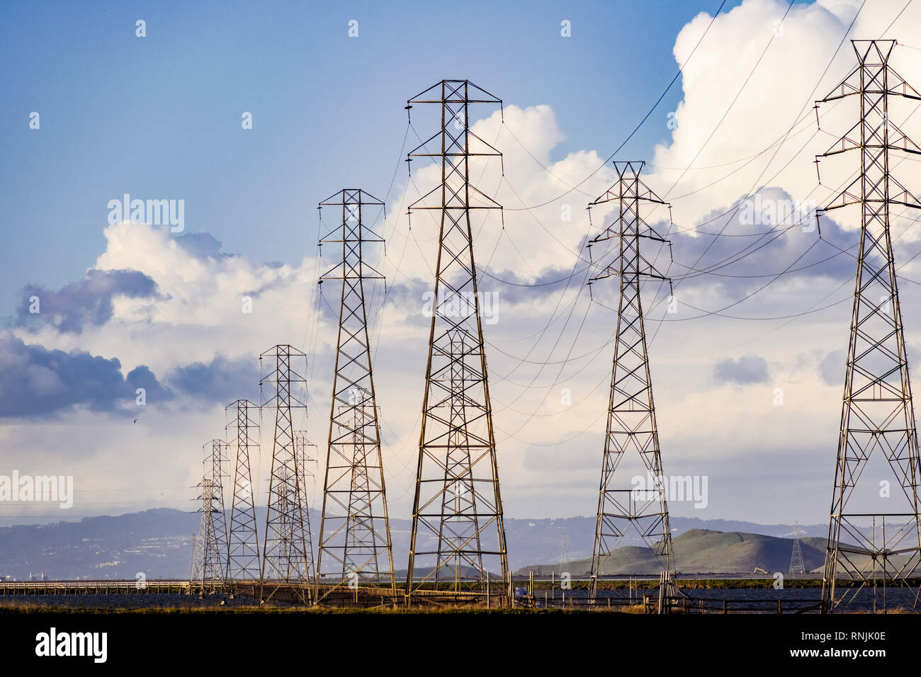High voltage electricity power lines and transmission towers crossing the ponds and marshes of south San Francisco Bay area, Mountain View, California Stock Photo