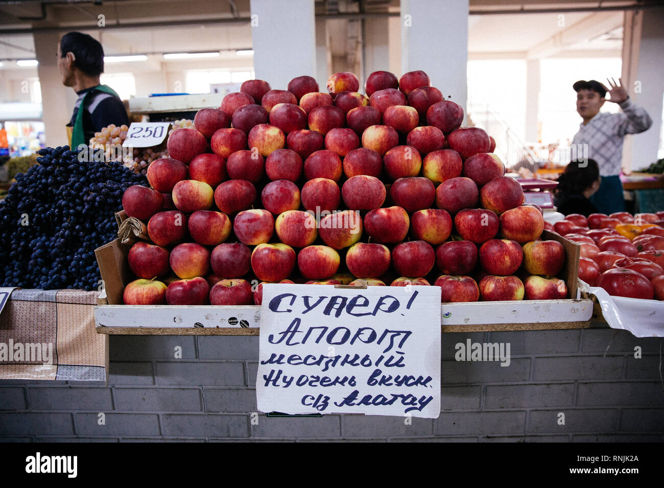 A fruit vendor that sells apples and grapes waiving at the Green Bazaar