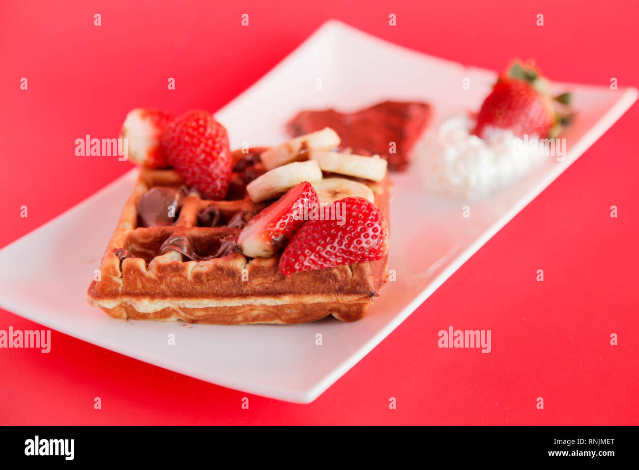 Strawberry and Banana flavour waffle with whipped cream and chocolate spread Stock Photo