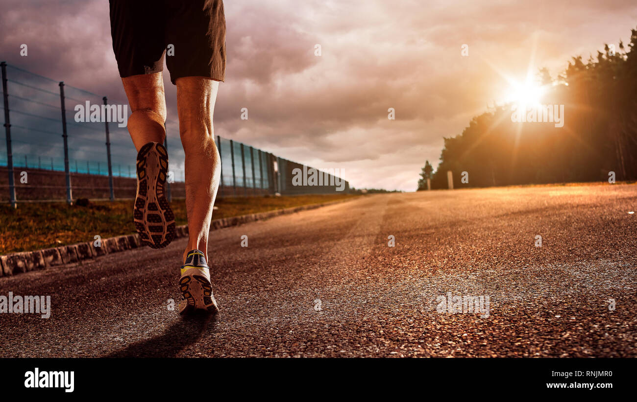 Runner runs up to the hill. On the top of the hill there is the sun that is a Symbol of success, new and better life. A new future and a better life Stock Photo
